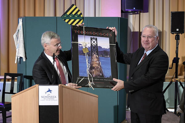 Bild vergr&ouml;&szlig;ern: Landrat Rolf Keil (links) �bergibt an den Direktor des IFA Hotel & Ferienparks Sch�neck Thomas Jahn (rechts)  ein Bild mit dem Titel "Verbindungen".