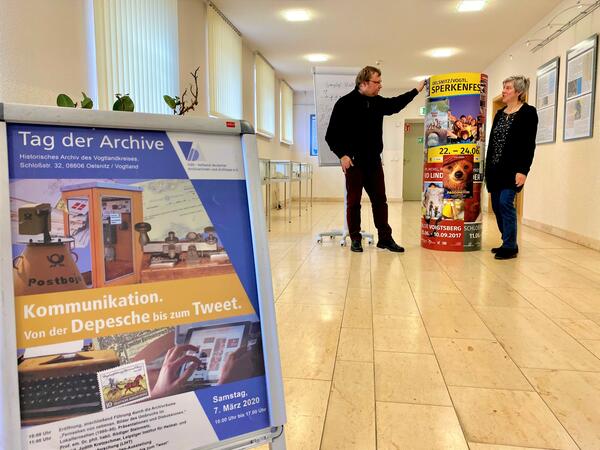 Bild vergr&ouml;&szlig;ern: Archivleiterin Sigrid Unger und Dr. Christian Espig stehen vor einer Litfa&szlig;s&auml;ule in der Archivalien-Ausstellung zum Thema "Kommunikation. Von der Depesche bis zum Tweet".