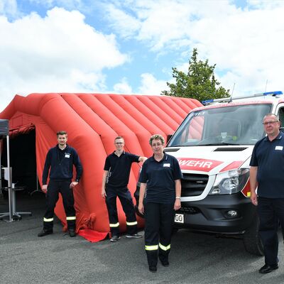 Bild vergr&ouml;&szlig;ern: Auf dem Bild stehen vier Mitglieder der Freiwlligen Feuerwehr Neumark vor einem Feuerwehrauto.