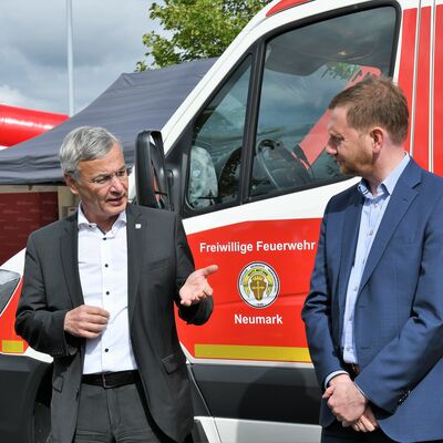 Bild vergr&ouml;&szlig;ern: Landrat Rolf Keil und Ministerpr&auml;sident Michael Kretschmer stehen vor einem Feuerwehrauto der freiwilligen Feuerwehr und unterhalten sich.