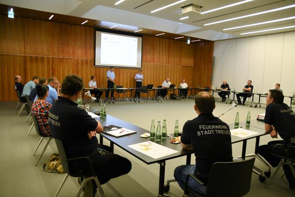 Bild vergr&ouml;&szlig;ern: Im Kreistagssaal sitzen mehrere Vertreter vogtl&auml;ndischer Feuerwehren und verfolgen die Pr&auml;sentation des Kompetenzzentrums f&uuml;r den Brand- und Katastrophenschutz. &Uuml;ber den aktuellen Stand informieren Kreisbrandmeister Gerd P&uuml;rzel und Thomas Schloss vom Katastrophenschutz.