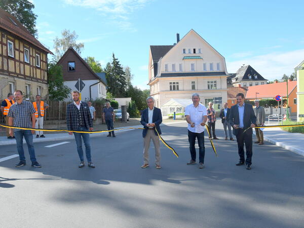 Bild vergr&ouml;&szlig;ern: Landrat Rolf Keil (Mitte) durchschnitt mit Neumarks B&uuml;rgermeister Sven K&ouml;pp (rechts), weiteren G&auml;sten und Bauschaffenden das symbolische Band zur Stra&szlig;enfreigabe. Foto: Landratsamt