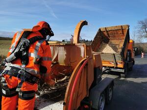Bild vergr&ouml;&szlig;ern: Das Bild zeigt, wie ein Mitarbeiter der Stra&szlig;enmeisterei die abgeschnittenen &Auml;ste zerkleinert. Daf&uuml;r schiebt er diese in eine spezielle Vorrichtung.