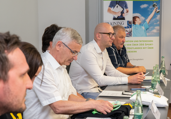 Bild vergr&ouml;&szlig;ern: Das Bild zeigt einige der Teilnehmer der Pressekonferenz zu den Vogtlandspielen. Landrat Rolf Keil freut sich �ber eine symbolische Goldmedaille und ein T-Shirt. Beides wurde ihm durch Steffen Fugmann �bergeben.