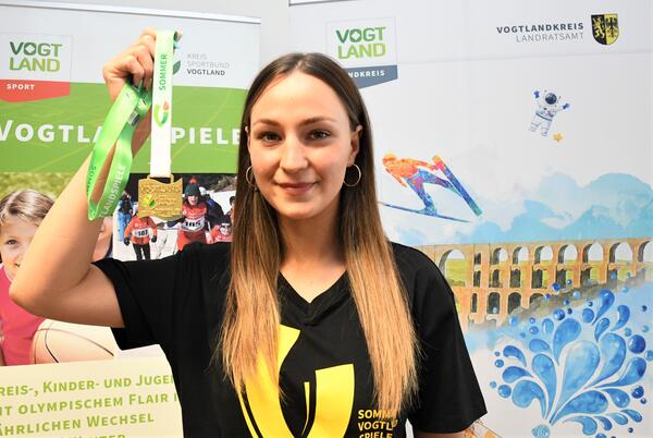 Bild vergr&ouml;&szlig;ern: Das Bild zeigt Gina Spranger. Die diesj�hrige Botschafterin hat einst bei den Vogtlandspielen ihre Sportlerkarriere begonnen. Auf dem Bild h�lt sie eine Goldmedaille in die Kamera.