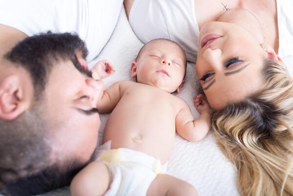 Bild vergr&ouml;&szlig;ern: Auf dem Bild sieht man eine junge Familie im Bett.
