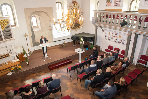 Bild vergr&ouml;&szlig;ern: Das Bild zeigt Landrat Rolf Keil auf der B&uuml;hne in der Kapelle in Neuensalz. Er h&auml;lt eine Rede und gibt die diesj&auml;hrigen Gewinner im Wettbewerb "Unser Dorf hat Zukunft" bekannt.
