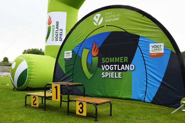 Bild vergr&ouml;&szlig;ern: Das Siegertreppchen vor dem gr�nen Logo der Vogtlandsommerspiele.