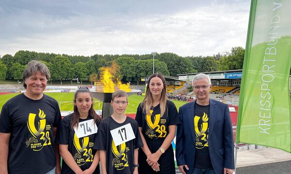 Bild vergr&ouml;&szlig;ern: Kreissportbund-Pr&auml;sident Steffen Fugmann und Landrat Rolf Keil  stehen mit Botschafterin Gina Spranger vor dem Olympischen Feuer. Entz&uuml;ndet haben dies die jungen Sportler Mark Tropsch und Sara Garboarova vom F&ouml;rderschulzentrum in Markneukirchen.