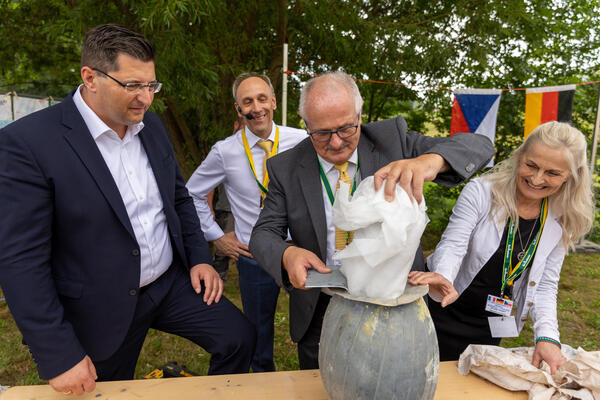 Bild vergr&ouml;&szlig;ern: Landrat Thomas Hennig (links), B&uuml;rgermeister Volker Bachmann (Mitte), Laurent Guillet und Gabriela Kaubisch &ouml;ffnen die Zeitkapsel.