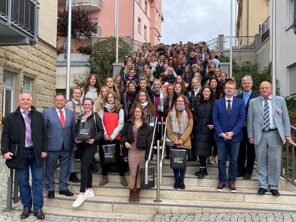 Bild vergr&ouml;&szlig;ern: Die neuen Studierenden der Studienakademie Plauen stehen versammelt auf einer Treppe.
