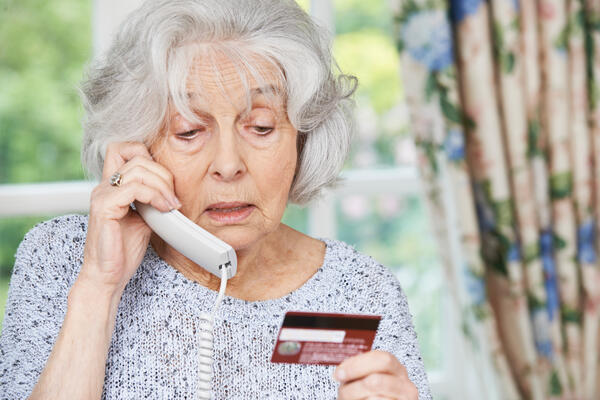 Bild vergr&ouml;&szlig;ern: Das Bild zeigt eine �ltere Frau, die gerade telefoniert und dabei ihre Bankkarte in der Hand h�lt. Offenbar sagt sie dem Gegen�ber ihre Kontonummer an. Dies sollte generell nie geschehen.