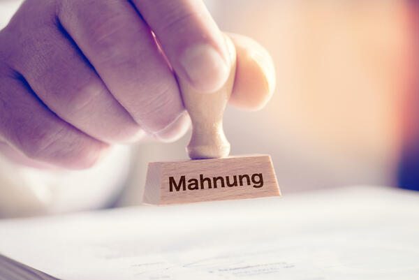 Bild vergr&ouml;&szlig;ern: Das Bild zeigt eine Hand, die einen Stempel mit der Aufschrift "Mahnung" h�lt.