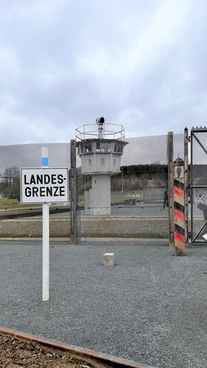 Bild vergr&ouml;&szlig;ern: Das Bild zeigt neben einem Schild mit der Aufschrift "Landesgrenze" einen ehemaligen Grenzturm.