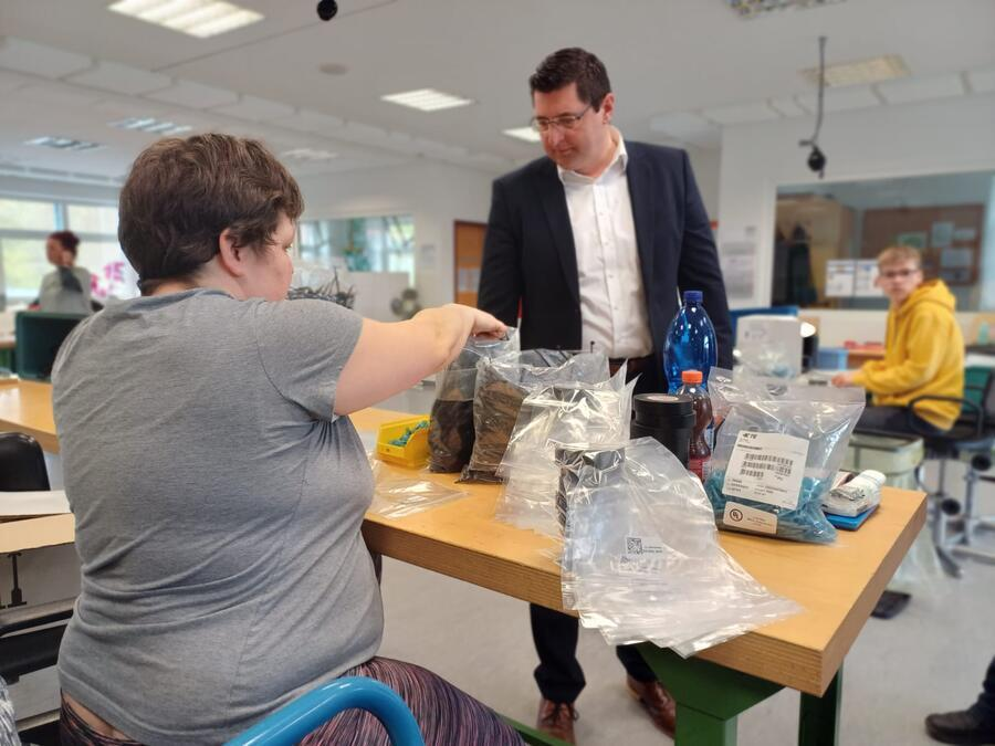 Landrat Hennig folgt den Arbeiten einer Angestellten der Werkstatt
