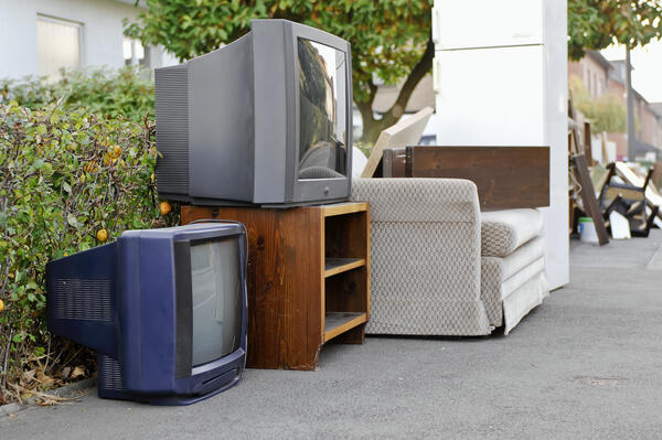 Bild vergr&ouml;&szlig;ern: Ein Sofa, zwei R�hrenfernseher, ein wei�er K�hlschrank sowie weitere Sperrm�llartikel und Elektro-Altger�te werden auf dem Gehweg zur Abholung bereitgestellt.