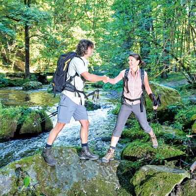Bild vergr&ouml;&szlig;ern: Das Bild zeigt einen Mann und eine Frau, wie sie im sch&ouml;nen Triebtal &uuml;ber die Felsen im Flussbett steigen.