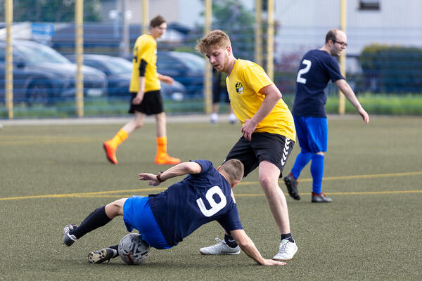 Bild vergr&ouml;&szlig;ern: Ein Spieler rutscht �ber das Feld. Ein anderer will ihn ausspielen, um an den Ball zu gelangen.