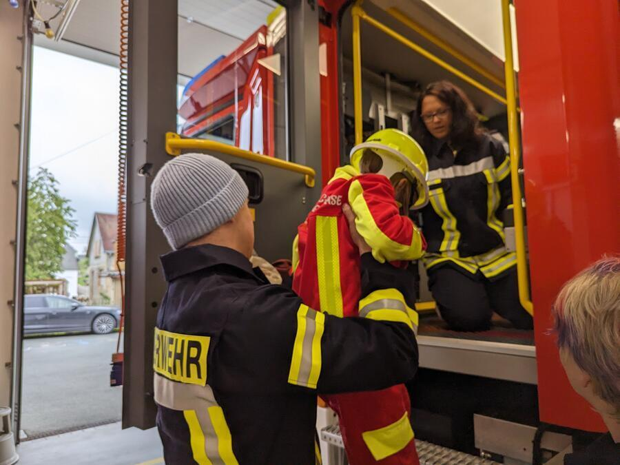 Ein Mann hebt ein Kind in ein Feuerwehrauto.