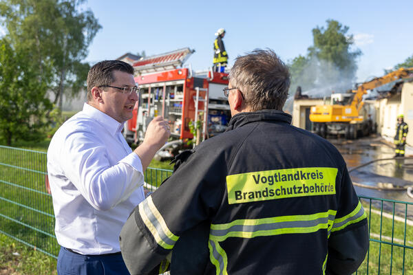 Bild vergr&ouml;&szlig;ern: Landrat Thomas Hennig l&auml;sst sich vom Kreisbrandmeister den Einsatz erkl&auml;ren