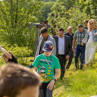 Bild vergr&ouml;&szlig;ern: Landrat Thomas Hennig l&auml;uft mit anderen G&auml;sten und Kindern &uuml;ber eine Wiese