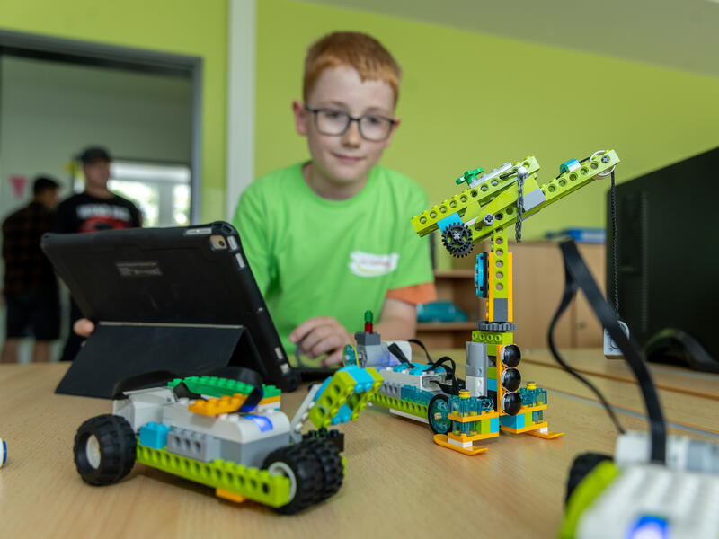 Ein Junge spielt mit einem ferngesteuerten Lego-Kran.