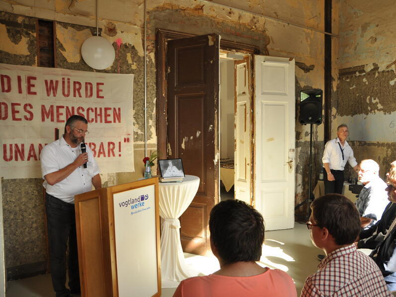 Gru&szlig;worte werden vor einer Ausstellung gehalten. Der Ausstellungraum ist alt.