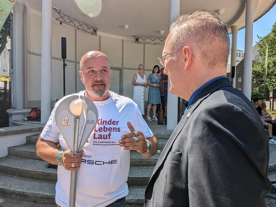 Ein Biker redet mit Dr. Axel Steinbach. Er h&auml;lt die Fackel in der Hand.