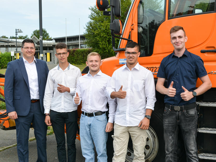 Landrat Thomas Hennig und vier junge M&auml;nner stehen vor einem Stra&szlig;enreinigungsger&auml;t.
