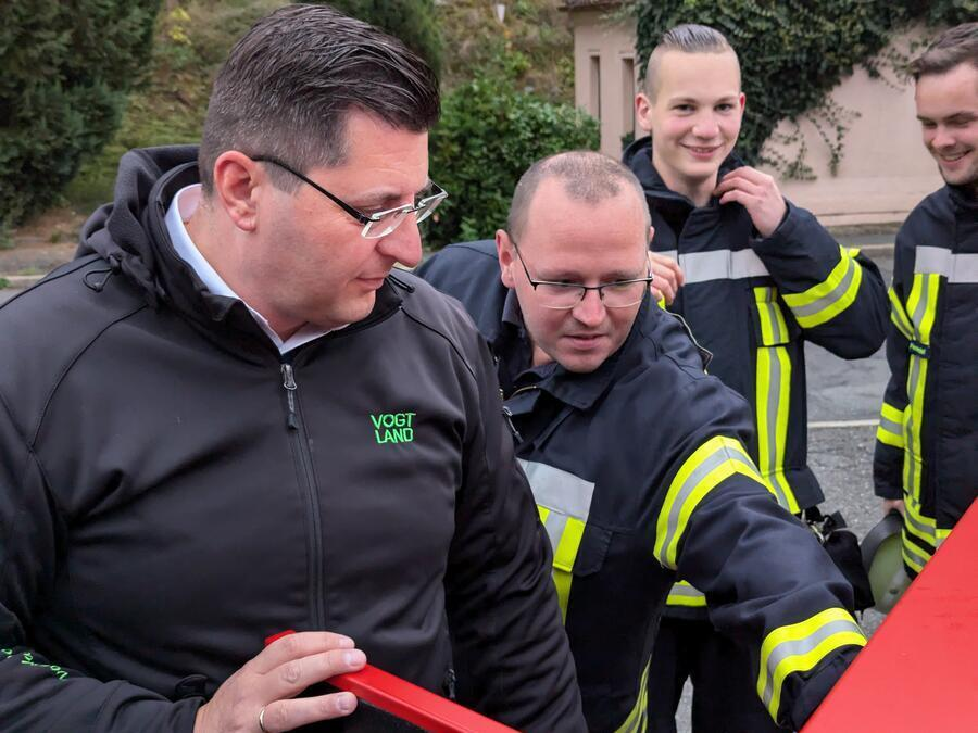 Der Landrat und ein Feuerwehrmann sehen sich das Ger&auml;t an.