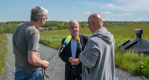 Bild vergr&ouml;&szlig;ern: Deponie Zobes: Landrat Rolf Keil im Gespr&auml;ch mit zwei Rundfunkjournalisten, im Hintergrund die Deponie Zobes.