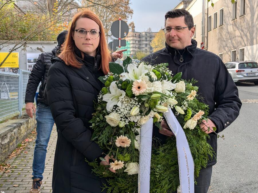 Landrat Thomas Hennig und Rika Kober halten einen wei&szlig;en Blumenkranz.
