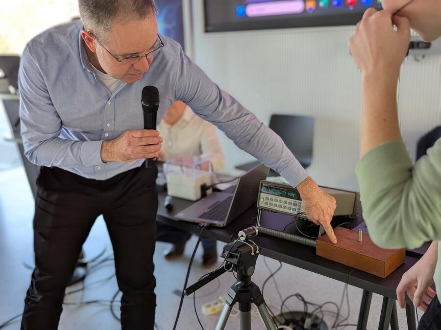Dr. Patrick Pertsch beugt sich &uuml;ber ein kleines Ger&auml;t. Es soll den Schall einer Stimmgabel &uuml;bertragen k&ouml;nnen.