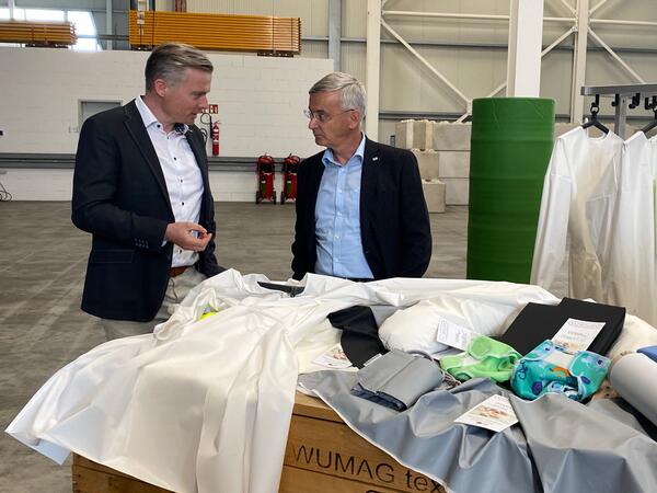 Bild vergr&ouml;&szlig;ern: Landrat Rolf Keil (rechts) im Gespr&auml;ch mit Unternehmer Axel Seidel, der in seiner Firma Seidel Moden unter anderem bakterien- und virendichte Schutzkittel mit Material der Firma Vowalon herstellt.