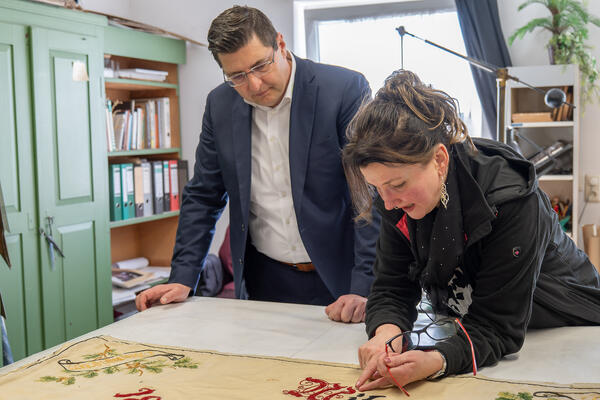Bild vergr&ouml;&szlig;ern: Zwei Menschen &uuml;ber einen Tisch gebeugt.
