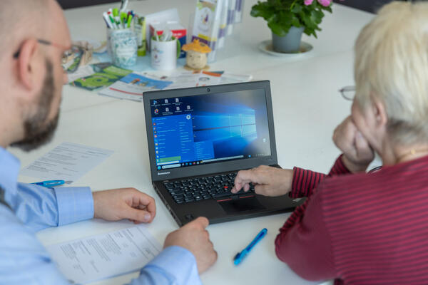 Bild vergr&ouml;&szlig;ern: Ein Medienberater erkl�rt einer �lteren Dame einige Funktionen am Laptop.