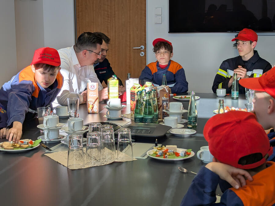 Die Kinder und der Landrat essen Kekse und trinken Kakao.