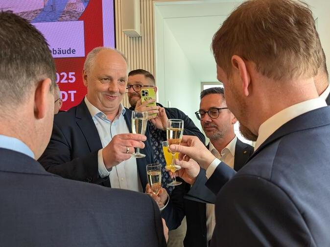 Vertretung aus Politik, Wirtschaft und Bildung sto&szlig;en mit Sekt an.