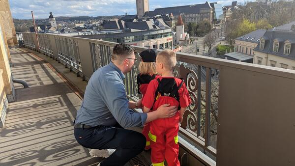 Bild vergr&ouml;&szlig;ern: Landrat Thomas Hennig schaut mit zwei Kindern vom Balkon.