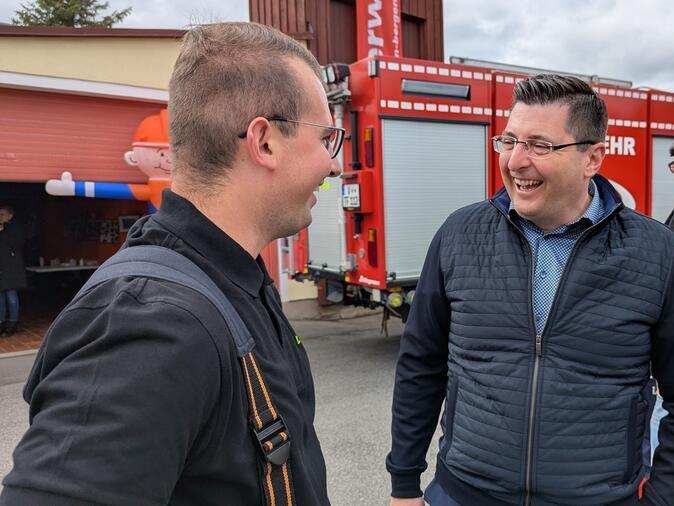 Landrat Thomas Hennig und ein Kamerad der Feuerwehr lachen.