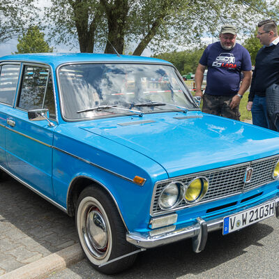 Bild vergr&ouml;&szlig;ern: Zwei M&auml;nner, darunter Landrat Thomas Hennig, betrachten einen blauen Lada-Oldtimer beim IFA-Treffen in Rebesgr&uuml;n. Im Hintergrund stehen weitere Fahrzeuge.
