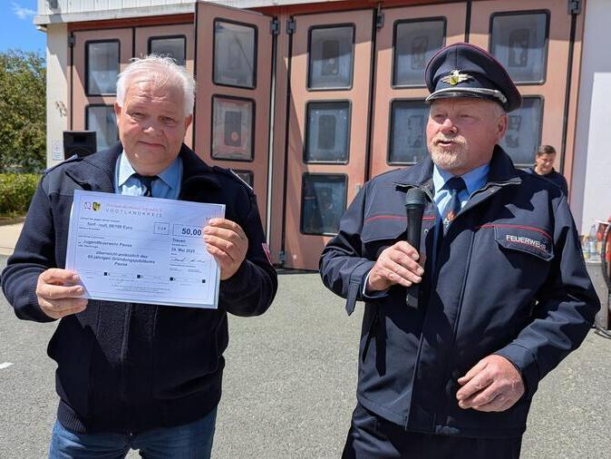 Der Jugendwart h&auml;lt einen Scheck hoch.
