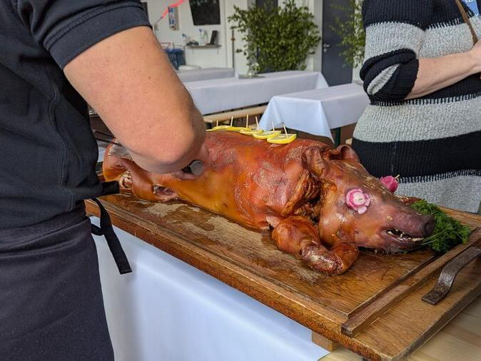 Ein Spanferkel wird angeschnitten.