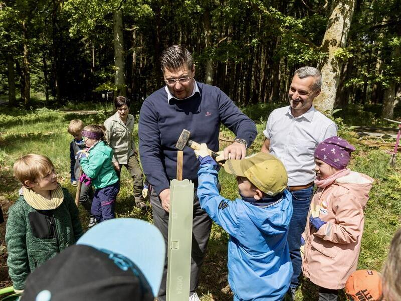 Landrat Thomas Hennig pflanzt mit Kindern B&auml;ume.