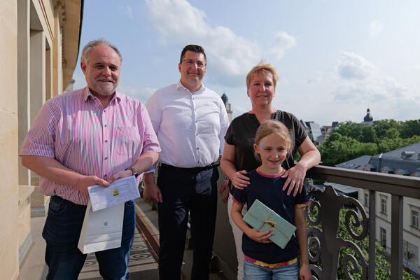 Bild vergr&ouml;&szlig;ern: Drei Gewinner und Landrat Thomas Hennig stehen auf dem Balkon des Landratsamtes.