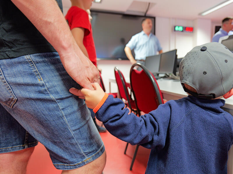 Ein Kind an der Hand seines Vaters.