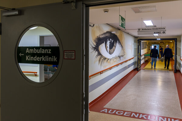 Bild vergr&ouml;&szlig;ern: Dr. Axel Steinbach geht einen Gang entlang. An der Wand ist das Bild eines Auges zu sehen.