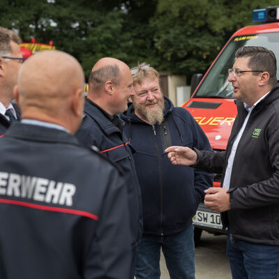 Bild vergr&ouml;&szlig;ern: Landrat Thomas Hennig spricht mit Feuerwehrleuten &uuml;ber den Nachwuchs und wie wichtig dieser ist.