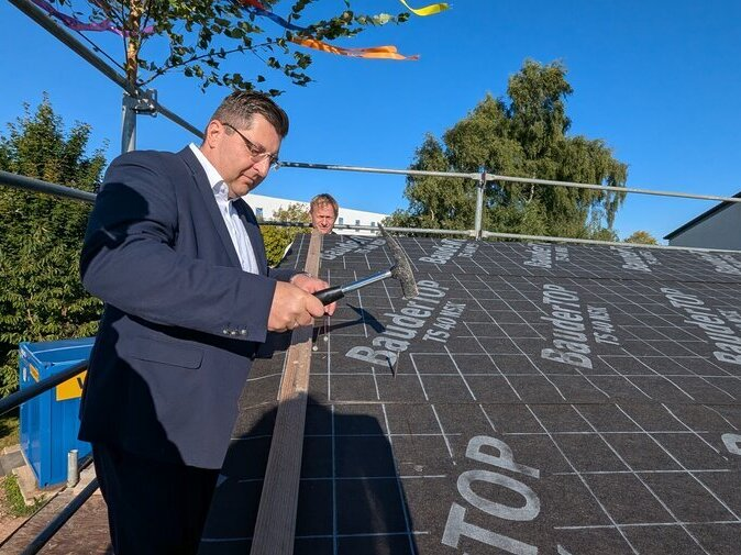 Landrat Thomas Hennig schl&auml;gt einen Nagel in einen Dachbalken.