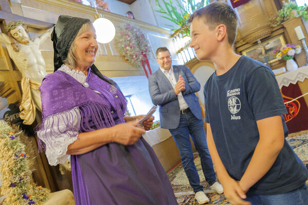 Bild vergr&ouml;&szlig;ern: Im Bild zu sehen: Geh&ouml;rte zu den j&uuml;ngsten Teilnehmern: Julius (rechts) bekam von Cornelia Hackel den Preis f&uuml;r seinen Erntekranz &uuml;berreicht. Landrat Thomas Hennig spendet im Hintergrund Applaus.
